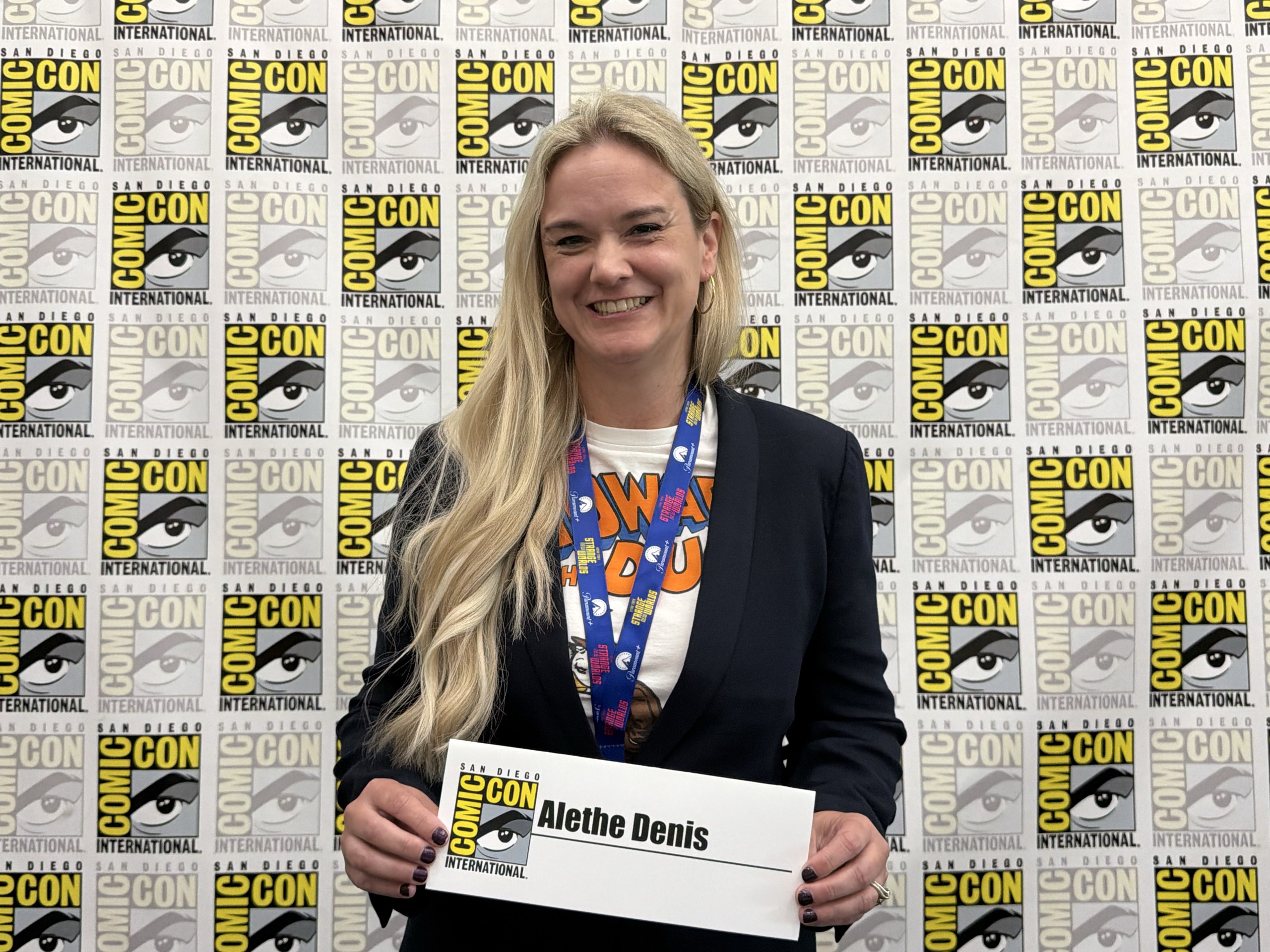 Alethe smiling at San Diego Comic-Con, wearing a Howard the Duck shirt beneath her blazer